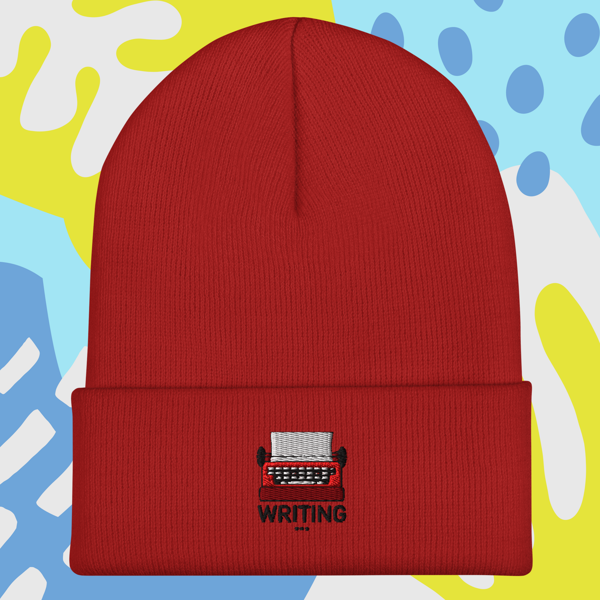 Red beanie with a typewriter and 'WRITING' embroidery on a colorful abstract background
